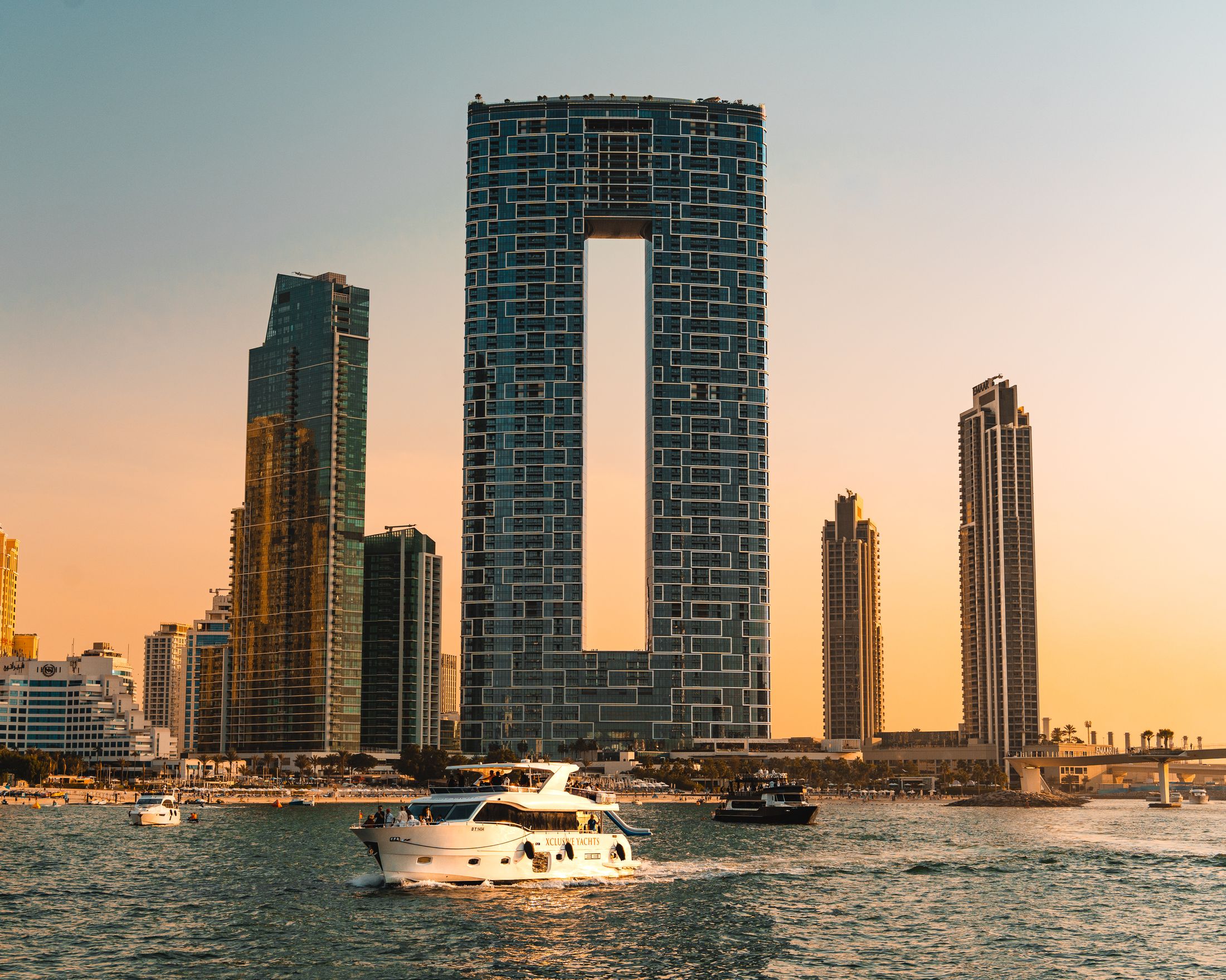 Luxury yacht cruising against Dubai's modern skyline at sunset